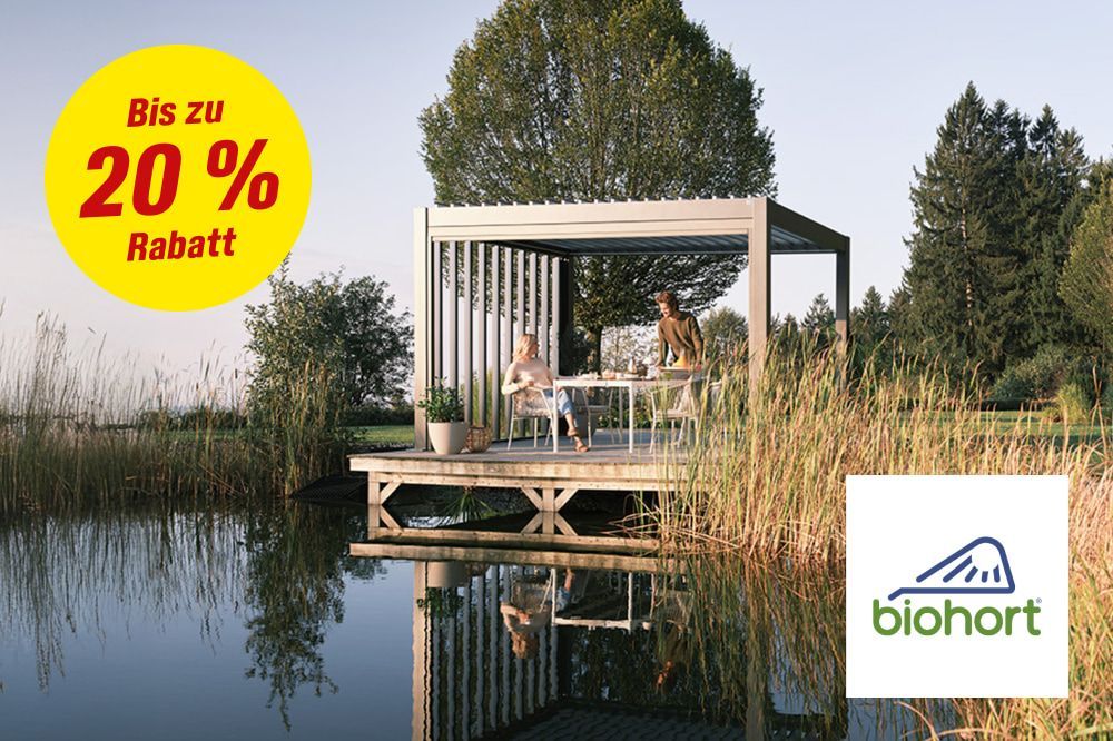 Zwei Personen sitzen in einem modernen Terrassendach am Wasser.